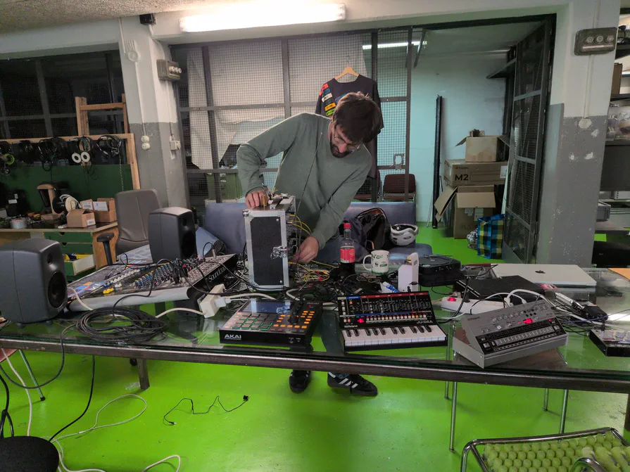 Der Synthesizer-Tisch: Hier wird Klang zur Interaktion Ein Tisch voller Synthesizer, Drum-Computer und Kabel, dahinter wird ein Gerät verkabelt